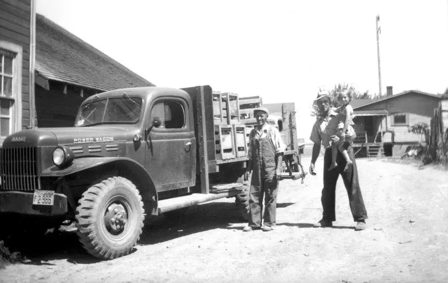 An old Power Wagon farm truck loaded with crates outside the farm buildings